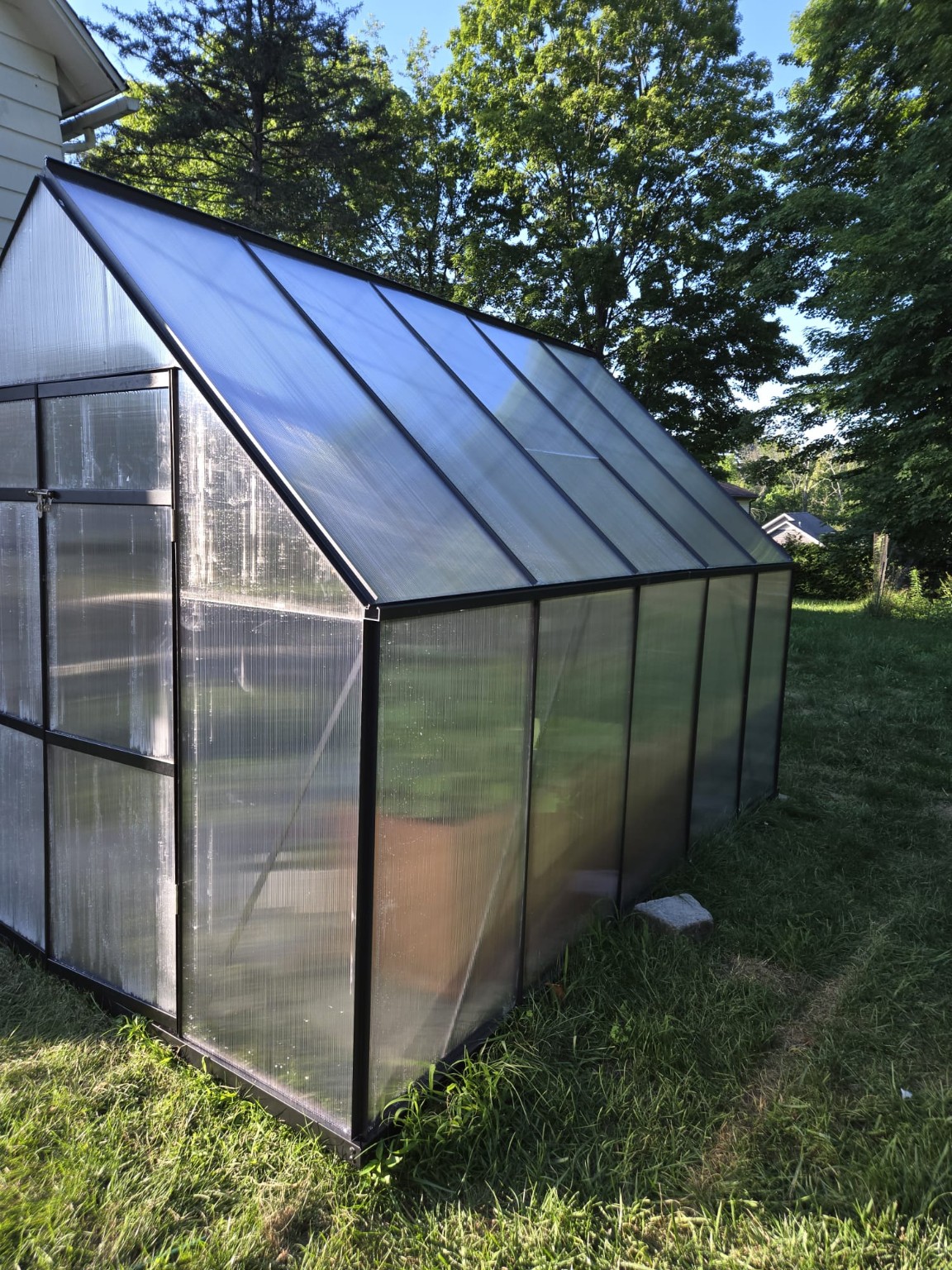 Completed freestanding greenhouse in a grassy yard